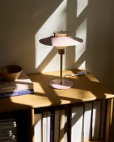 Rivoli Bordlampe Rosa fra Halo Design på et skrivebord med bøger - roligt lys over arbejdspladen Rivoli Bordlampe Rosa fra Halo Design på et skrivebord med bøger - roligt lys over arbejdspladen